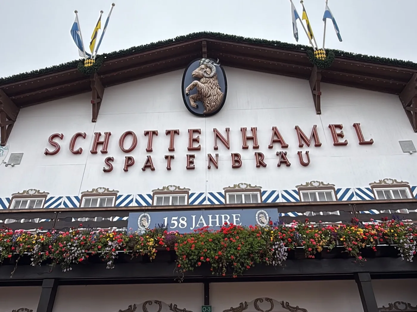 Fachada da Schottenhamel-Festhalle, com o carneiro da Spatenbräu no frontão e a placa "158 Jahre" na sacada. Foto minha, setembro de 2026.